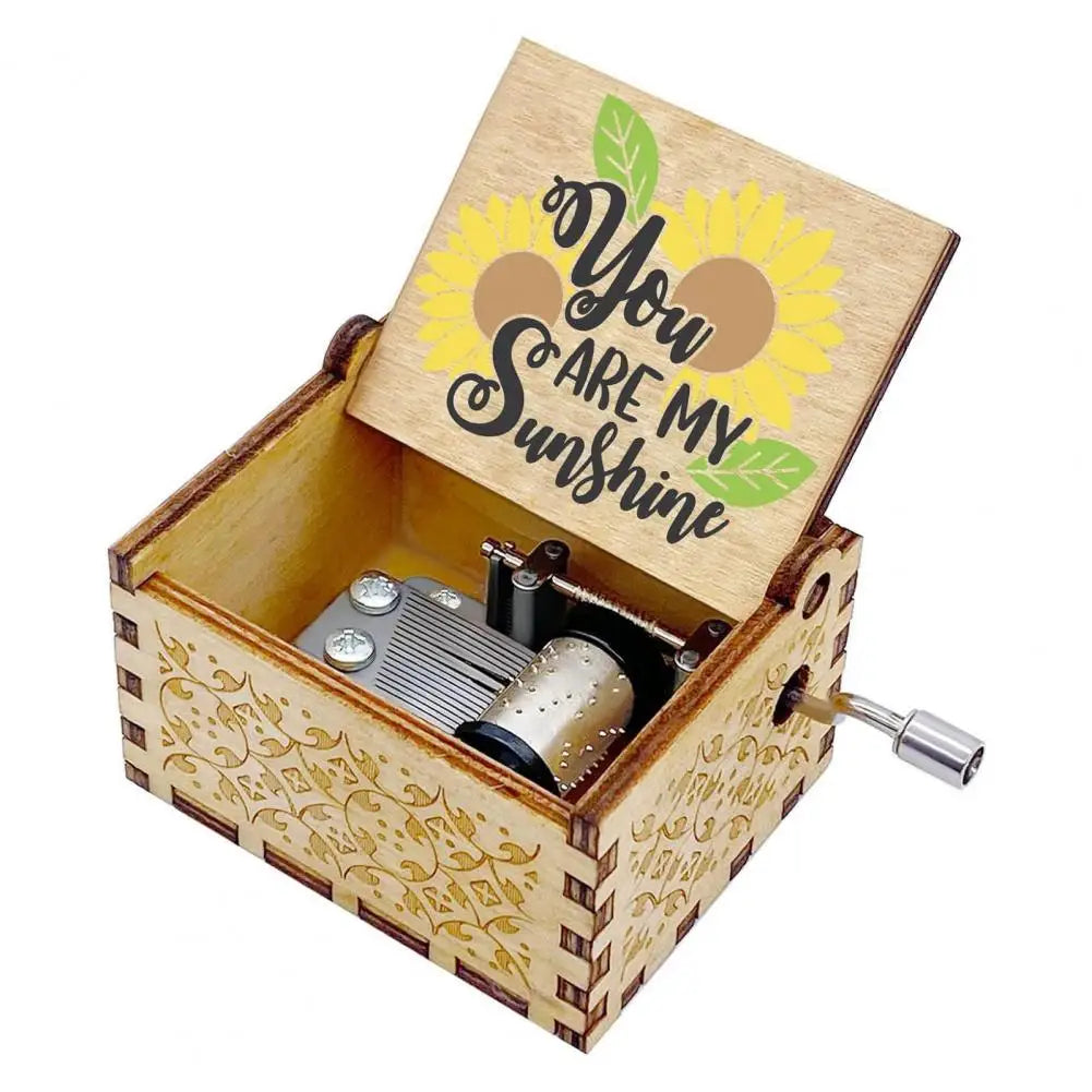 A mini wooden music box with a lid featuring the text You Are My Sunshine and a hand crank mechanism.