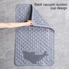 A gray rectangular bath mat with a back vacuum suction cup design is shown being held by a hand.