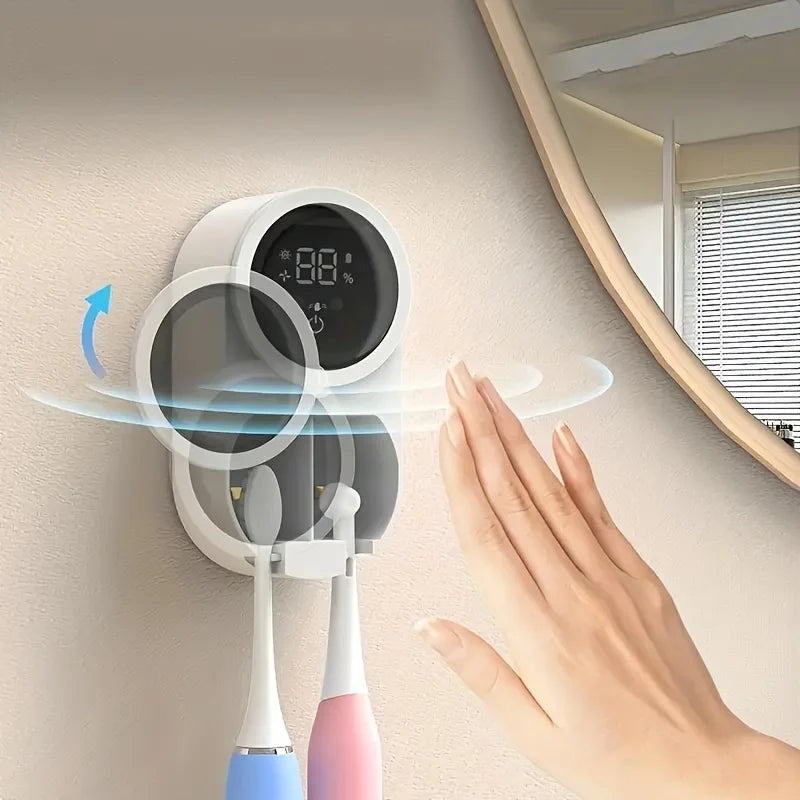 A hand is interacting with a wall-mounted automatic rotating toothbrush dryer device.