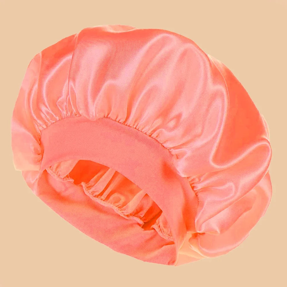 A solid peach satin wide brim shower cap shown from above.