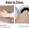 A beige waffle weave bathroom rug being shaken off for cleaning and a similar rug being washed in a machine.