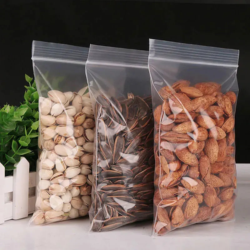 Tres bolsas ziplock transparentes llenas de semillas y frutos secos como semillas de lino, almendras y sésamo