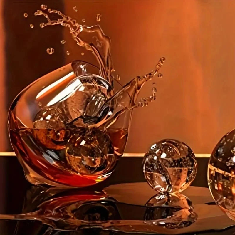 A glass of amber liquid is being poured into a bowl, creating splashing water and ice cubes on a reflective surface.