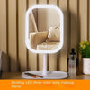 A white LED desktop mirror with a round frame reflects a person in a neutral-toned room.