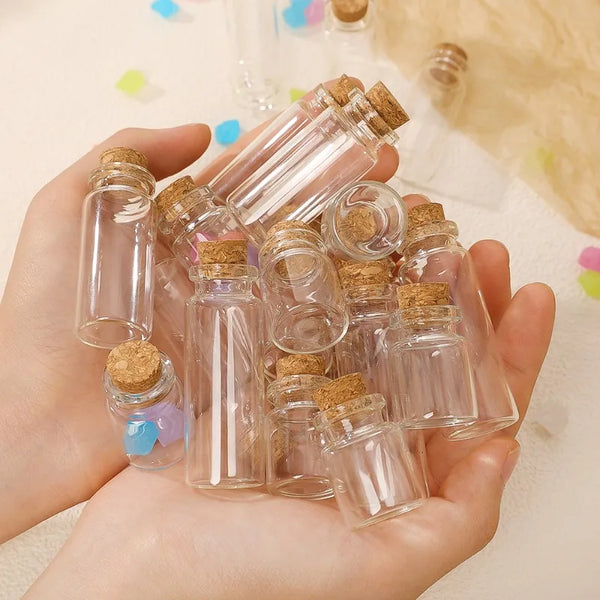 Une main tient plusieurs petits flacons en verre avec des bouchons de liège pour la décoration DIY.