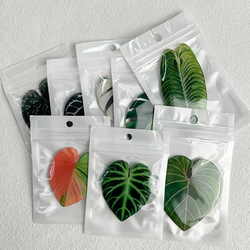A set of realistic green and variegated plant leaves used as fridge magnets, packaged in clear plastic bags.