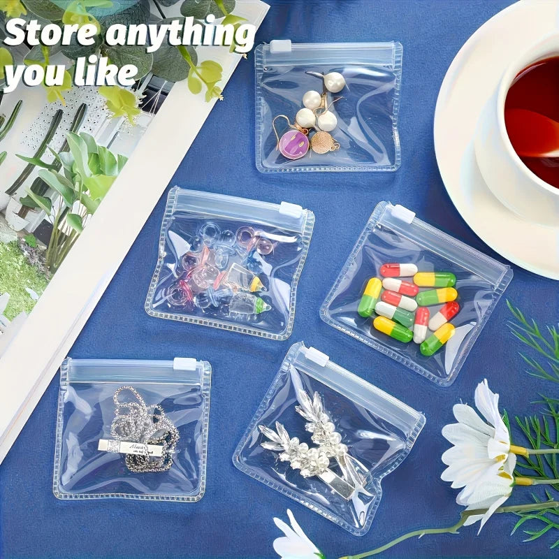 Clear plastic organizer bags containing various small items like jewelry and pills on a blue surface.