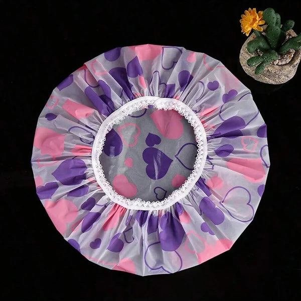 A circular decorative shower cap made of purple and pink tissue paper with a white trim, next to a small succulent plant.