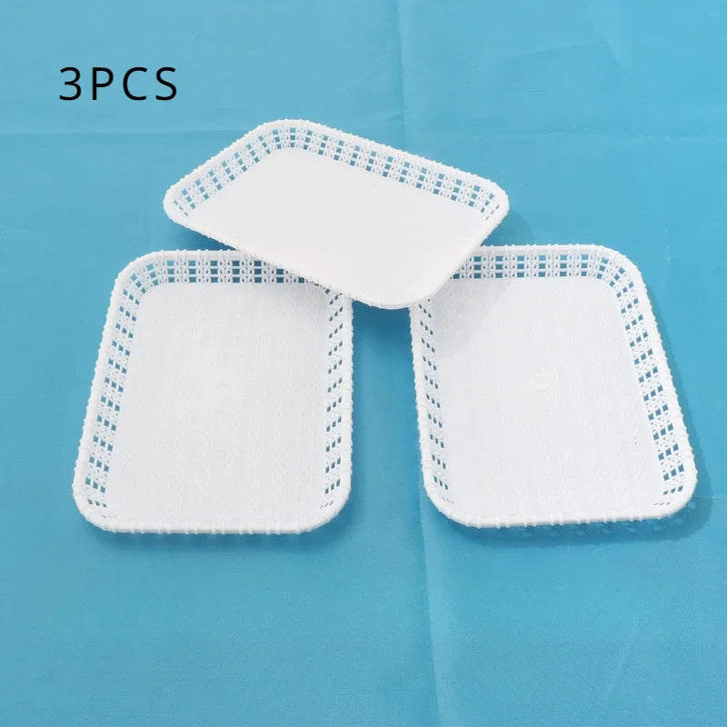 Three white plastic dessert stands or trays with decorative mesh edges are displayed on a blue surface.