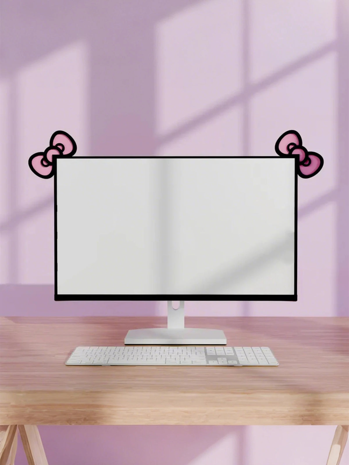 Un moniteur d'ordinateur avec une base blanche et un clavier sur un bureau en bois, encadré par des décorations en nœuds rose