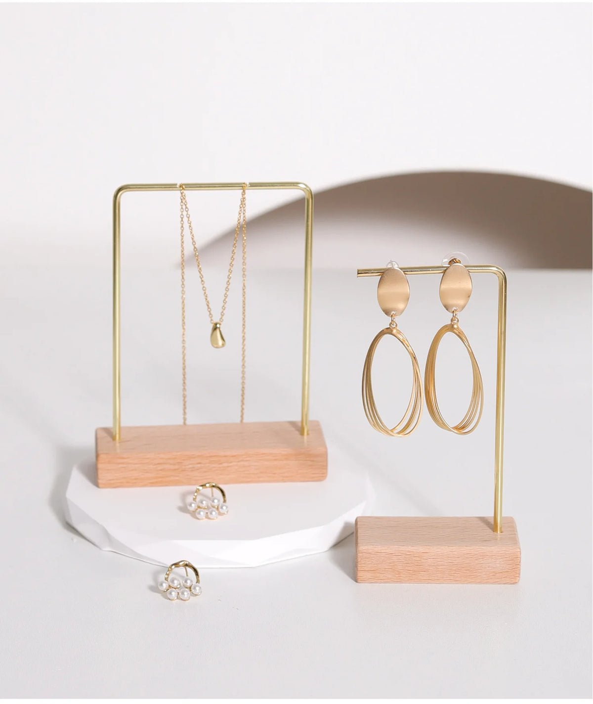 A gold-toned wooden jewelry display rack holding delicate necklaces and earrings.