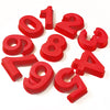 Red silicone number cake molds shaped like the digits 1 through 9 scattered on a white background.