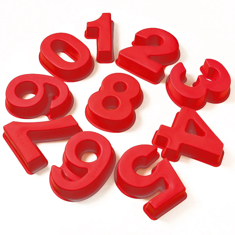 Red silicone number cake molds shaped like the digits 1 through 9 scattered on a white background.