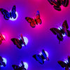 A display of luminous 3D butterfly wall lights in shades of pink, purple, and blue against a dark background.