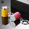 A silver metal coin tube keychain with a yellow and pink design is shown against a dark background.