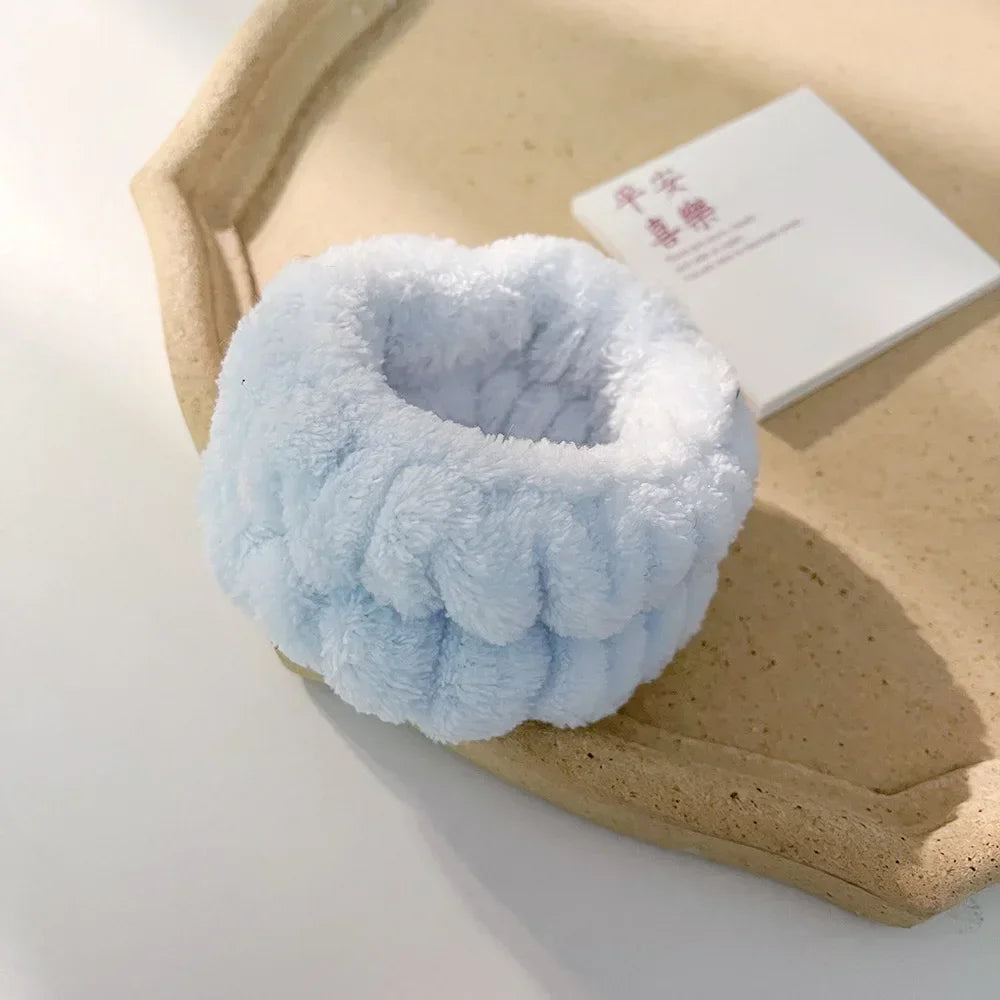 A light blue microfiber wrist sweatband set for face washing and skincare resting on a beige tray.