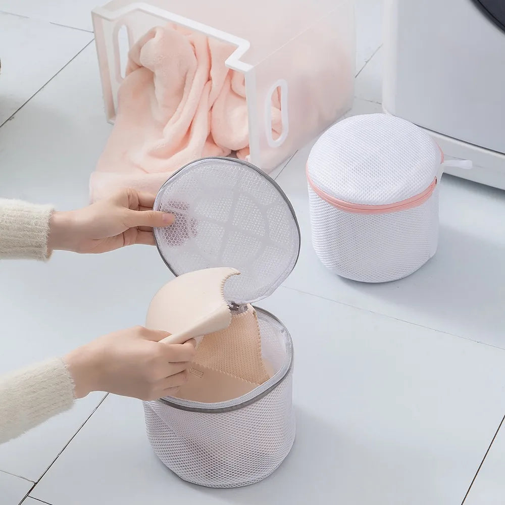 Hands are shown using a reusable zippered laundry bag to put pink towels inside.