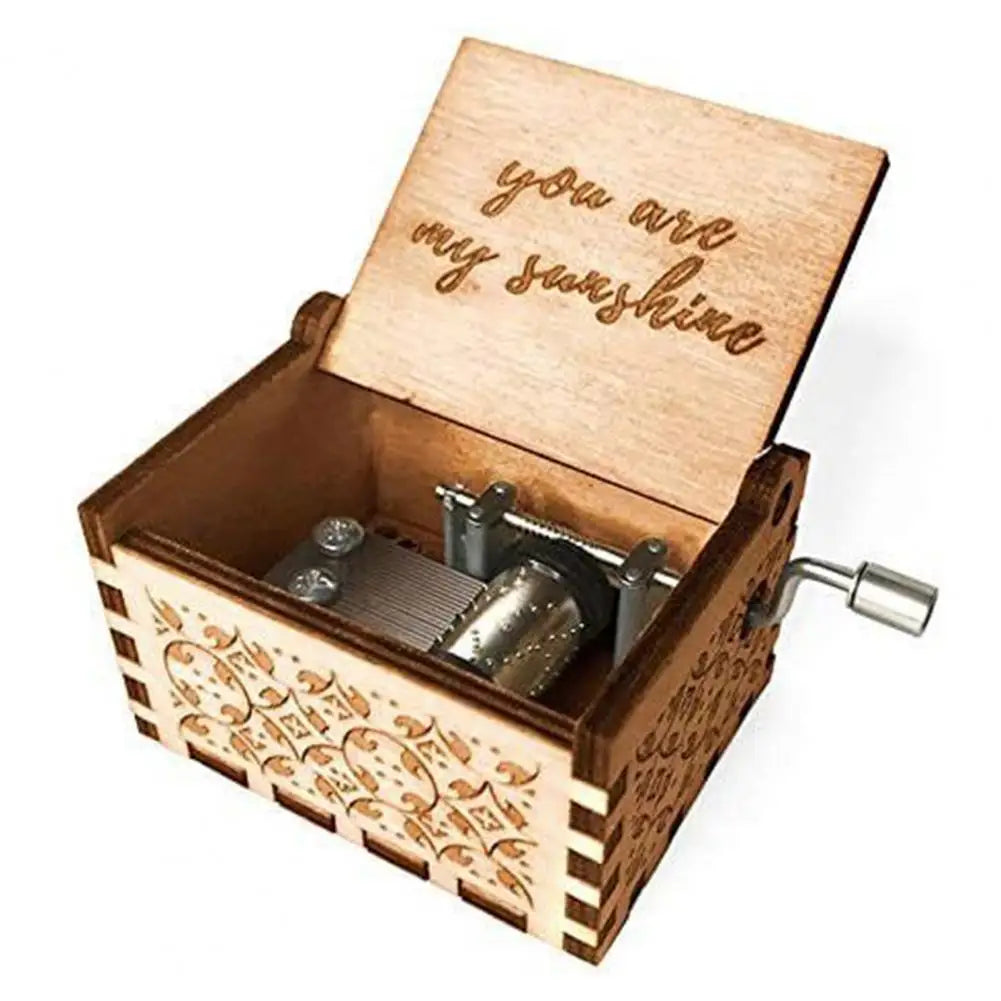 A small wooden music box with an open lid featuring engraved text and a hand crank mechanism.