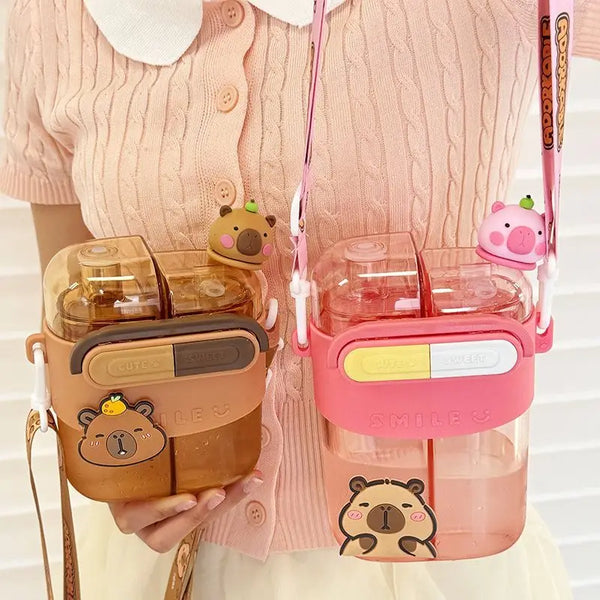 A pink cartoon capybara double-sided water bottle with a straw is held against a light pink knitted sweater.