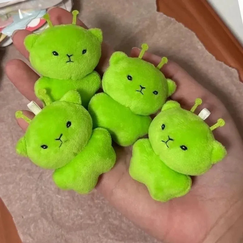 Five bright green plush cats arranged on a hand