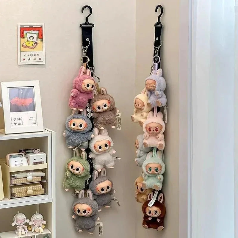 A display rack featuring various Labubu figurines in different colors and sizes hanging on a wall.