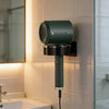 Étagère murale pour sèche-cheveux en vert foncé installée sur un mur carrelé à côté d'un miroir.