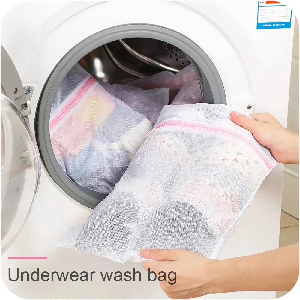 Eine Hand legt einen feinen Wäschebeutel in den Trommel einer weißen Waschmaschine.