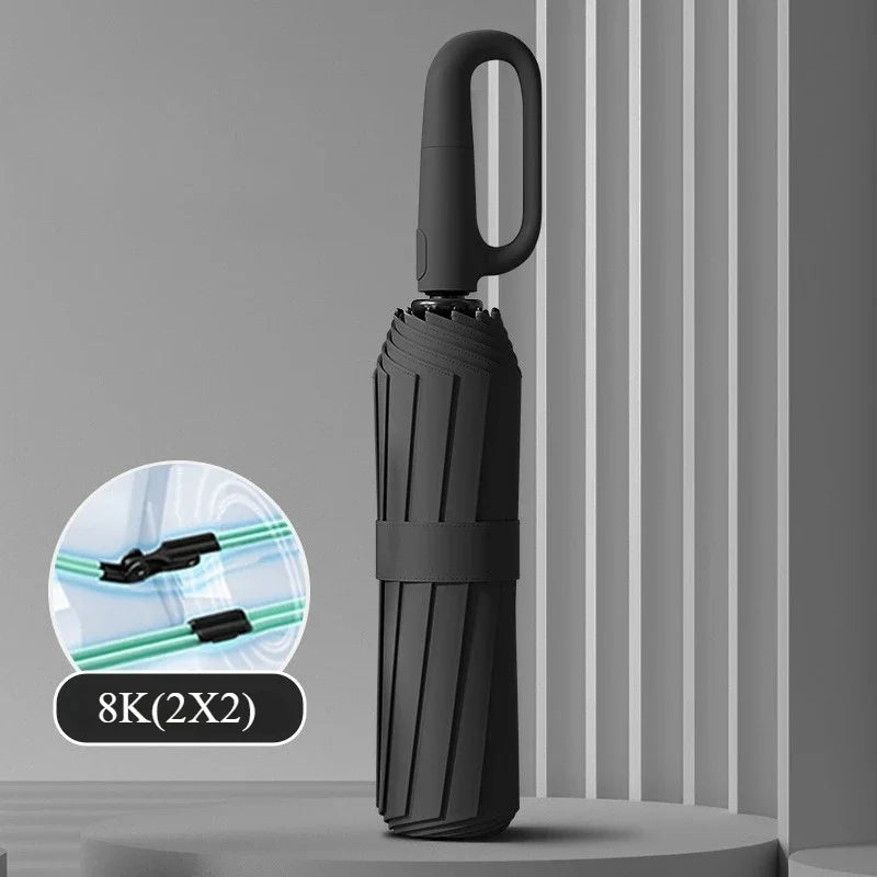 A black automatic folding umbrella with a handle is shown against a gray background.