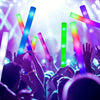 Eine Menge hebt Glow-Sticks in der Luft bei einem Konzert oder einer Party mit leuchtend lila und grünem Licht.