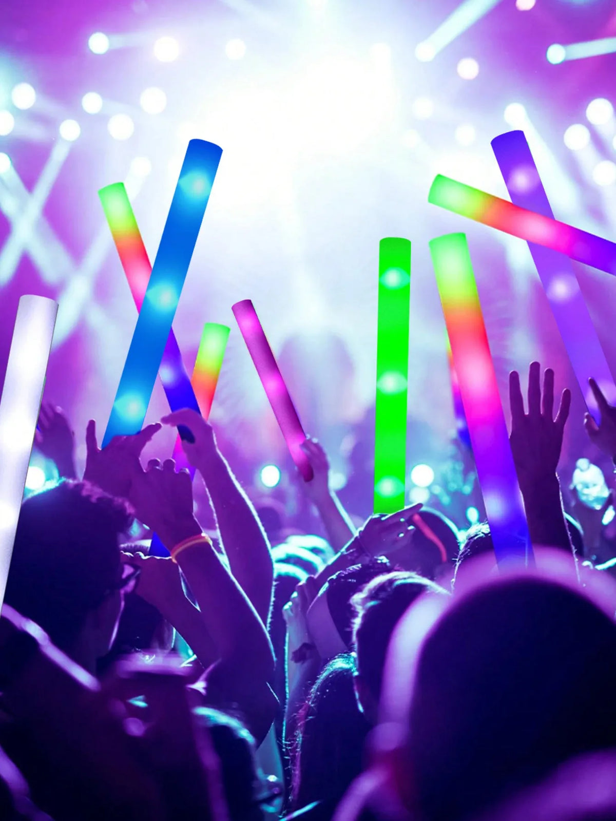 Eine Menge hebt Glow-Sticks in der Luft bei einem Konzert oder einer Party mit leuchtend lila und grünem Licht.