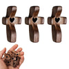 Three handcrafted wooden pocket crosses with heart cutouts shown next to a hand holding more crosses