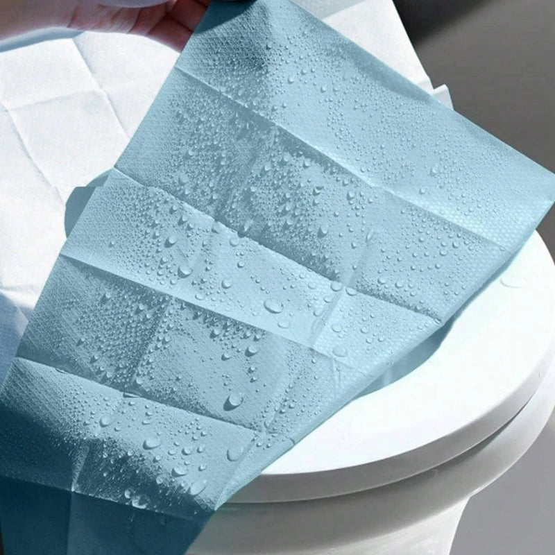 Gefaltete hellblaue Einweg-Toilettendeckung mit Wassertropfen.