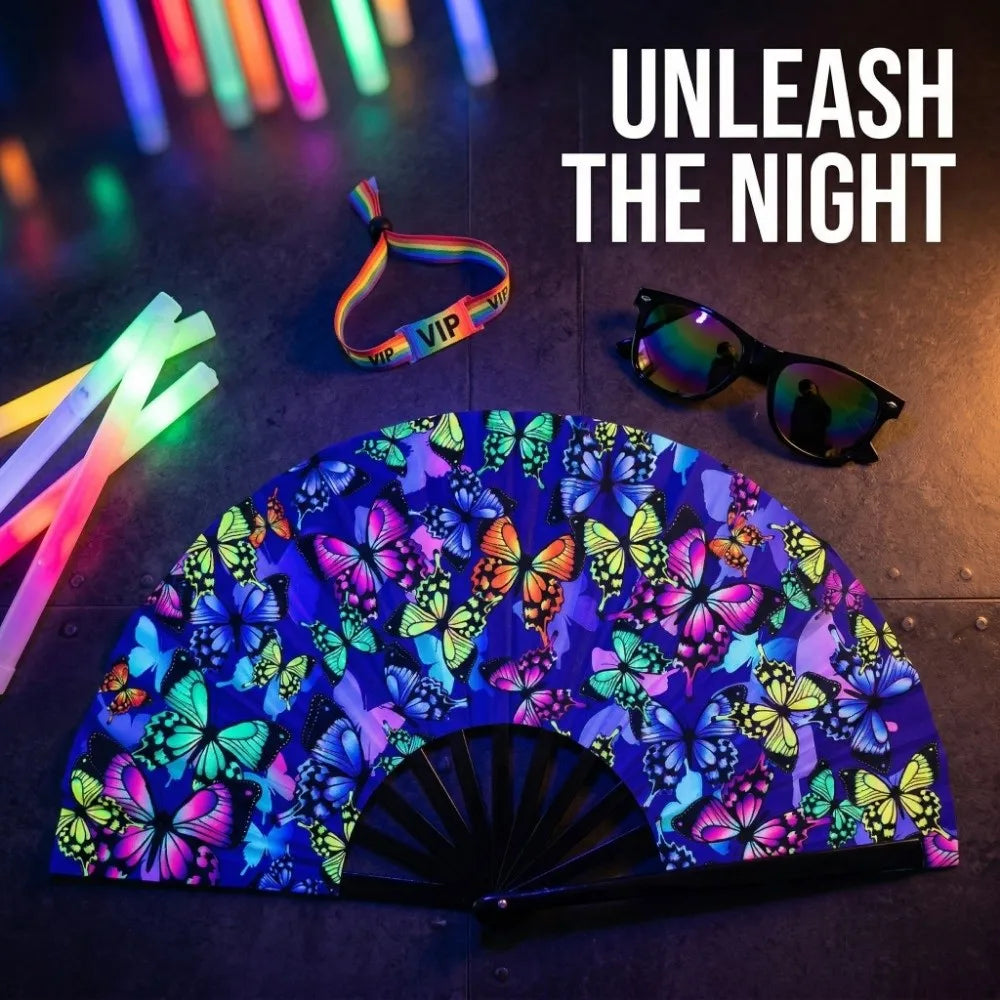 A purple and blue holographic gradient rave hand fan is displayed on a dark surface with sunglasses and a colorful strap.