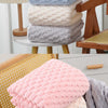Stack of pink, blue, and gray thickened microfiber bath towels on a wooden surface.
