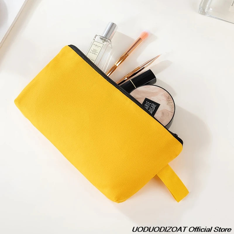 A yellow zipper bag holding makeup brushes and a circular mirror on a white surface.