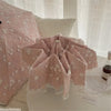 A pink full-automatic embroidered sun umbrella is displayed on a white surface next to sheer curtains.
