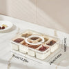 Clear plastic snack organizer tray with eight compartments holding various dried snacks on a white marble surface