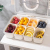 A clear 8 compartment snack organizer tray filled with various fruits like apples, plums, oranges, and bananas.