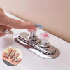 A hand presses a flower-shaped toilet flush button on a chrome flush plate.