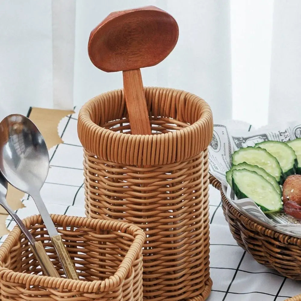 A stack of handwoven rattan serving baskets, including a tall cylindrical basket and a smaller square basket, with wooden spo