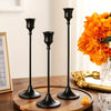 A set of three elegant black metal candle holders displayed on a wooden surface.