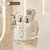 A clear glass storage rack with a stainless steel bunny figurine and two white glass bottles for bathroom products.
