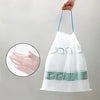 A hand holds a white drawstring trash bag with a blue loop, showing the clear plastic and printed labels.