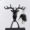 A black vintage deer head wall hook with antlers and a leather strap holding various keys.