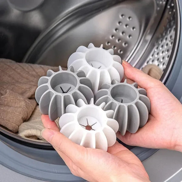 A hand holds several reusable silicone laundry balls for pet hair and lint removal inside a washing machine drum.