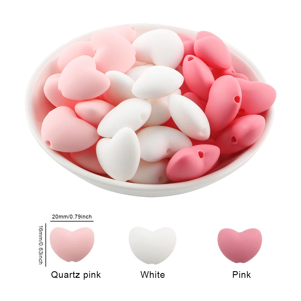 A bowl filled with 10 silicone charm beads shaped like hearts in pink and white colors
