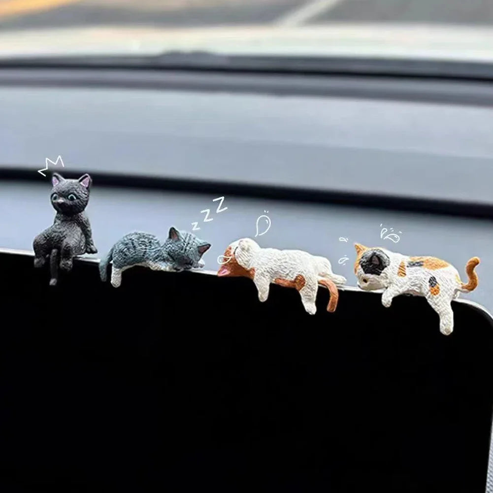 A set of four cute healing cat figurines lined up on a car window sill.
