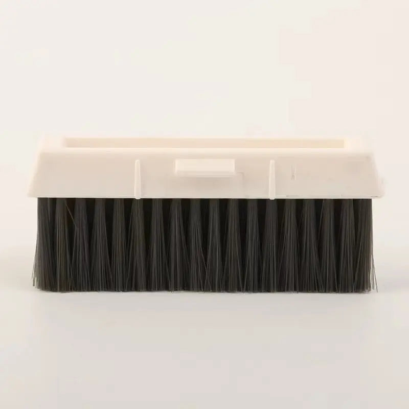 Cepillo de limpieza rectangular con cerdas negras y mango de plástico blanco para limpiar ventanas y rieles.