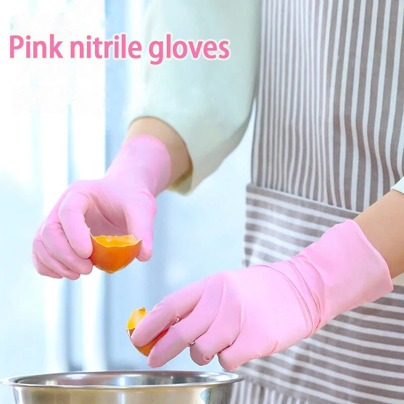 A hand wearing pink nitrile gloves is holding an orange piece of fruit over a metal bowl.