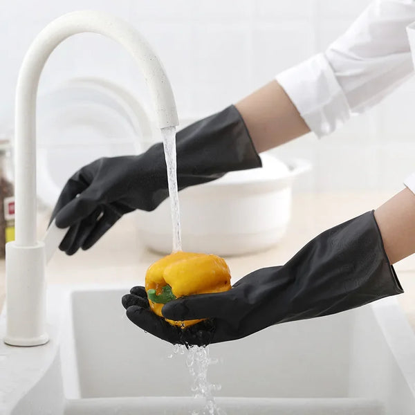 A hand wearing a black rubber cleaning glove is dripping water from a faucet into a white sink.
